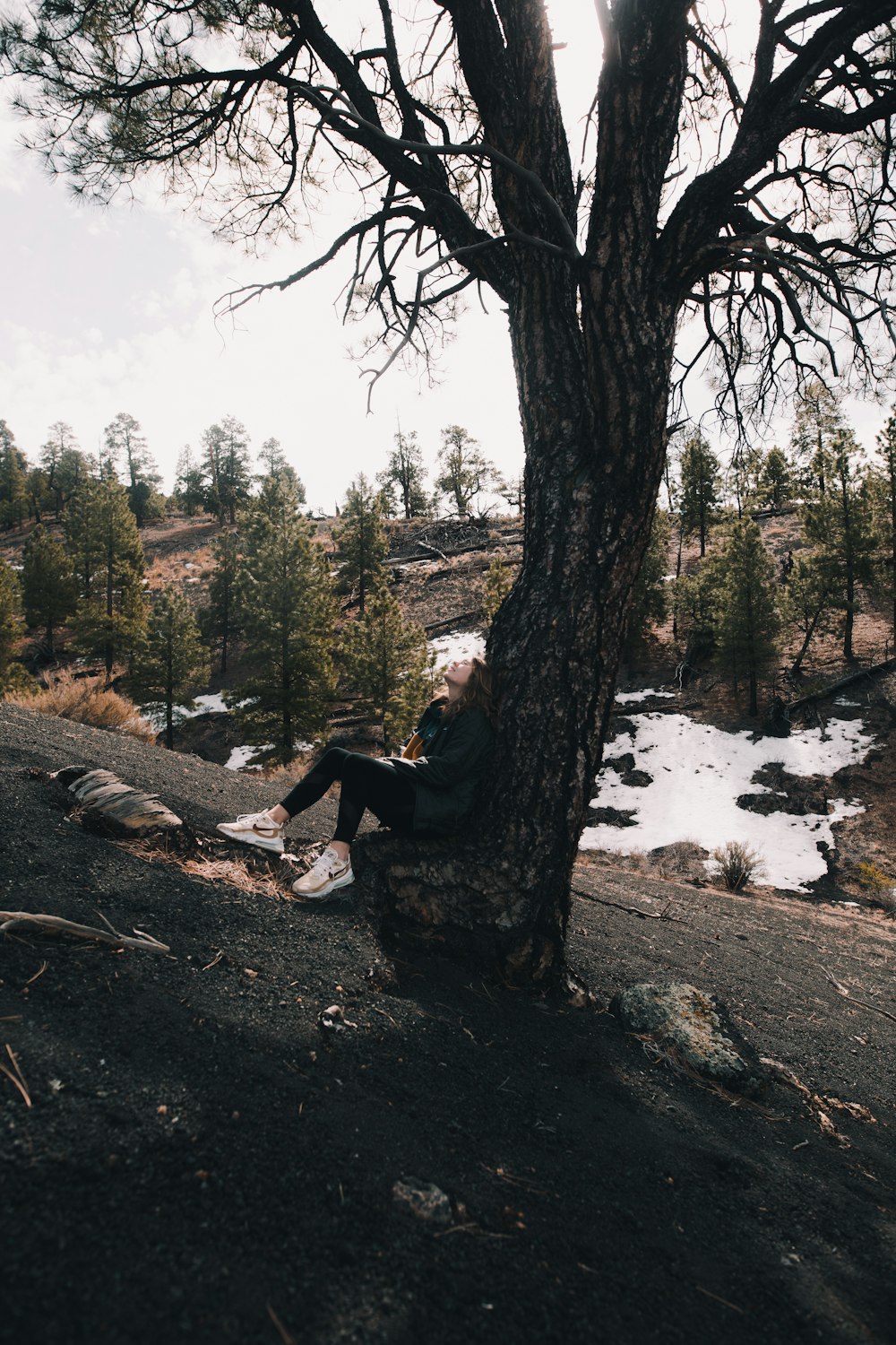 woman in black jacket sitting on rock near river during daytime