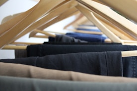 A pair of tailored trousers hanging neatly on a wooden hanger