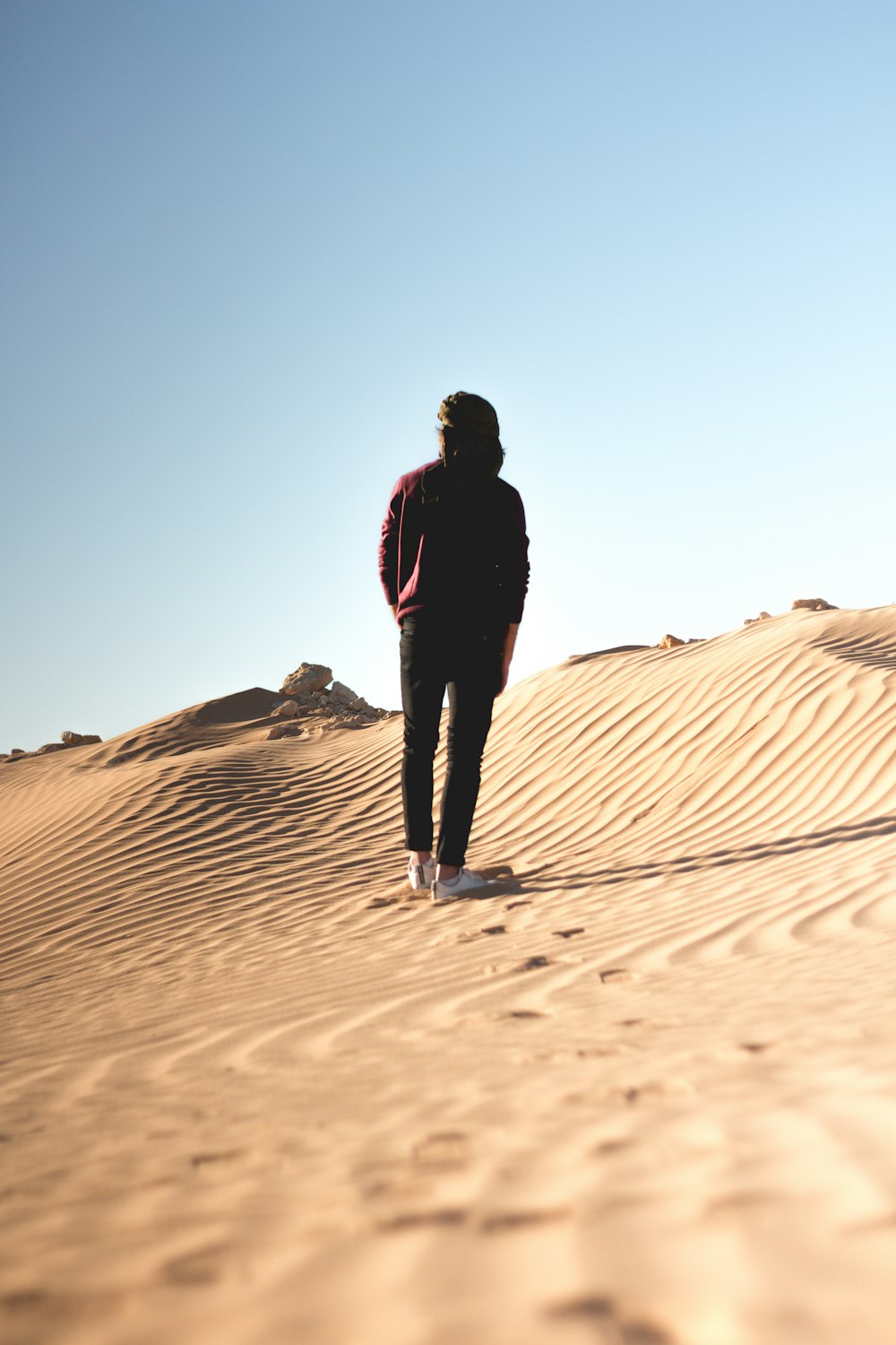 Hombre con chaqueta negra caminando en el desierto durante el día