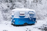 A custom flatbed camper parked beside a snowy mountain, showcasing its sturdy build and insulated windows.