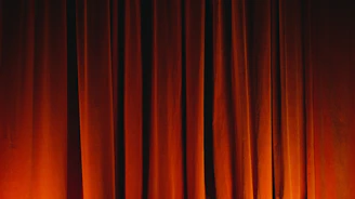 Close-up of vintage theater curtains glowing softly under stage lights, suggesting artistic ambiance.