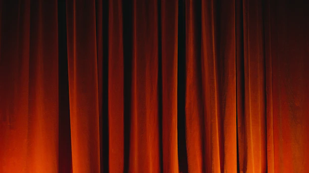 Close-up of vintage theater curtains glowing softly under stage lights, suggesting artistic ambiance.