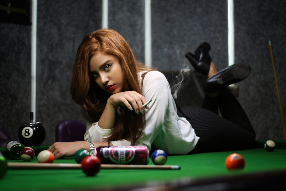 woman in white long sleeve shirt sitting on billiard table