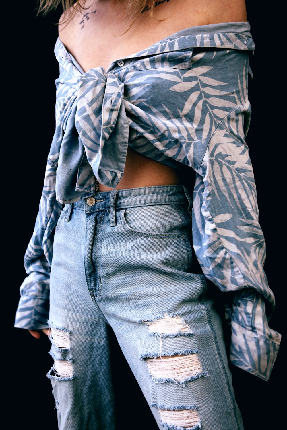 Femme en chemise à manches longues fleurie grise et noire et jean en denim bleu