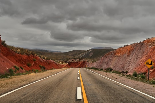 gray concrete road between brown mountains under gray clouds during daytime in Jujuy Argentina