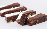 Close-up of a tray filled with assorted artisanal brownies topped with powdered sugar and nuts.
