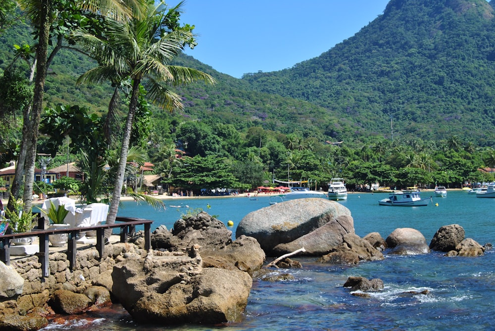 barco branco e azul no mar perto da montanha verde durante o dia