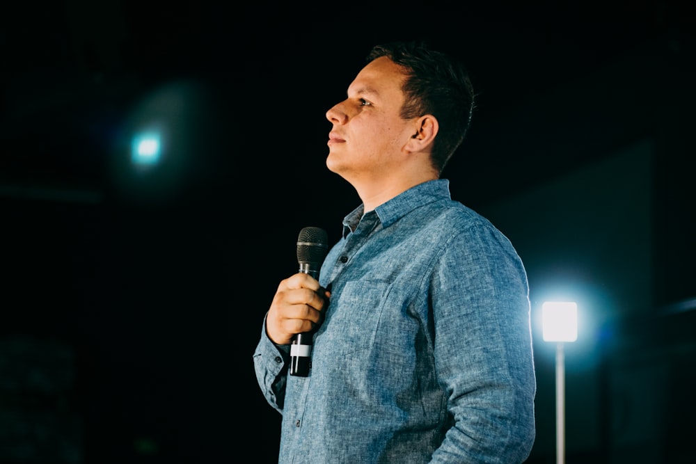 man in blue denim jacket holding microphone