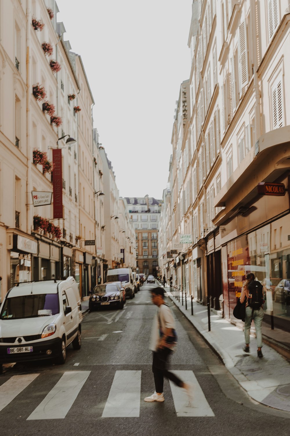 a person walking across a cross walk in a city