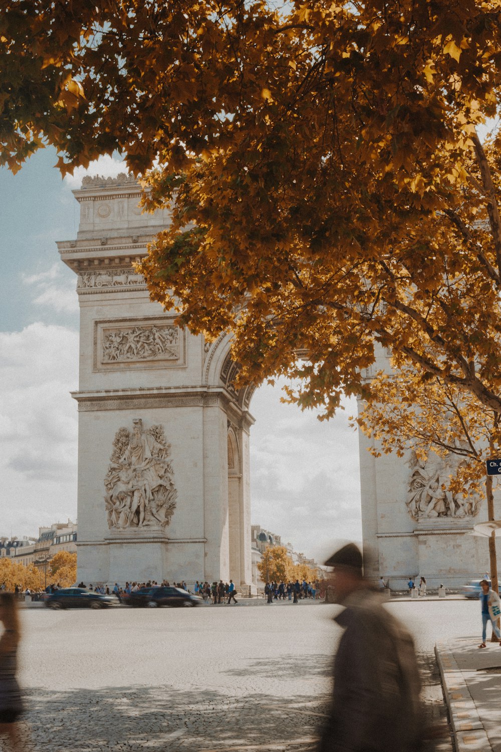 a man walking down a street past a tall clock tower