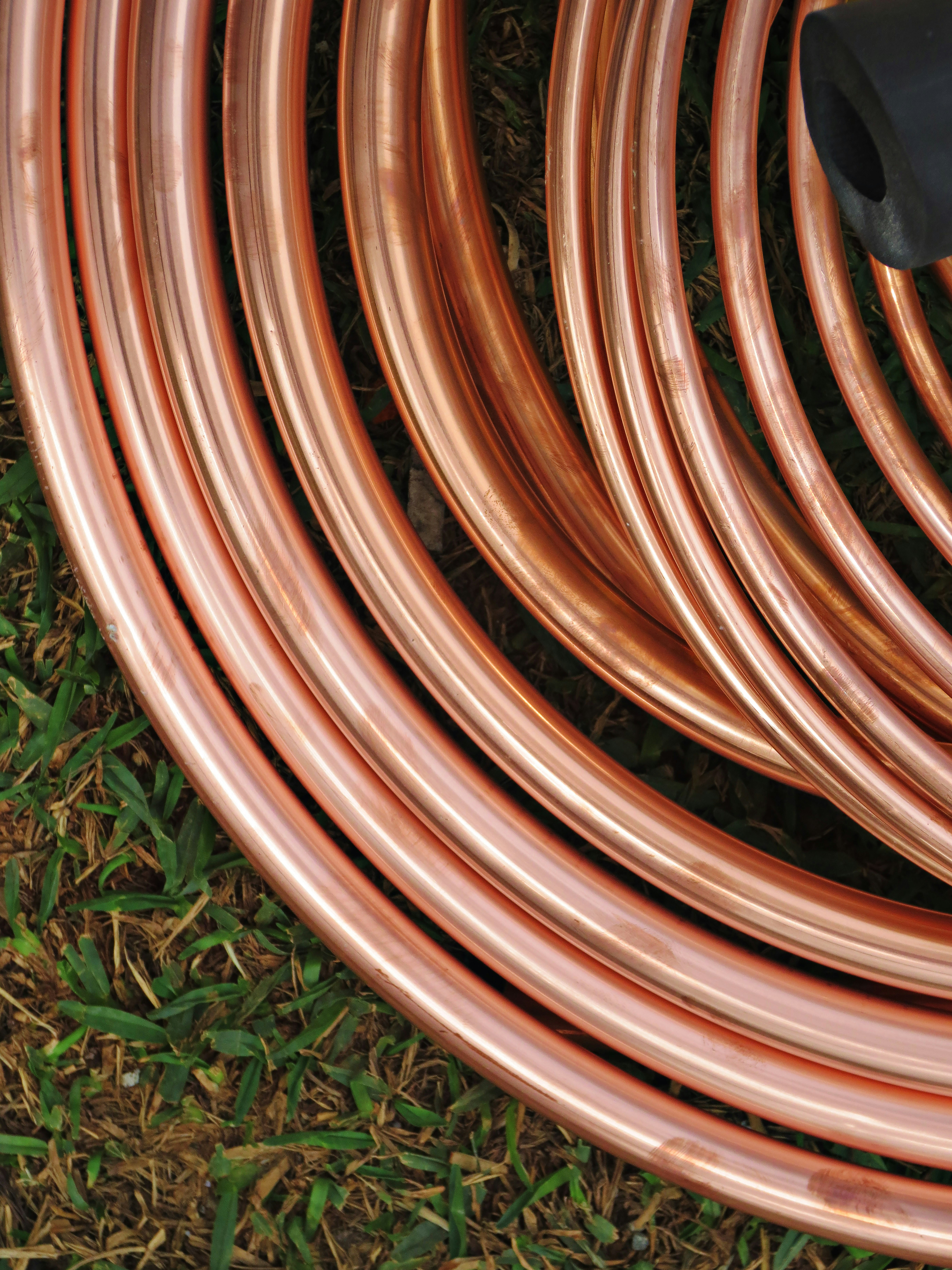 Gleaming copper pipes and wire coils in a well-lit metal yard with orange tones
