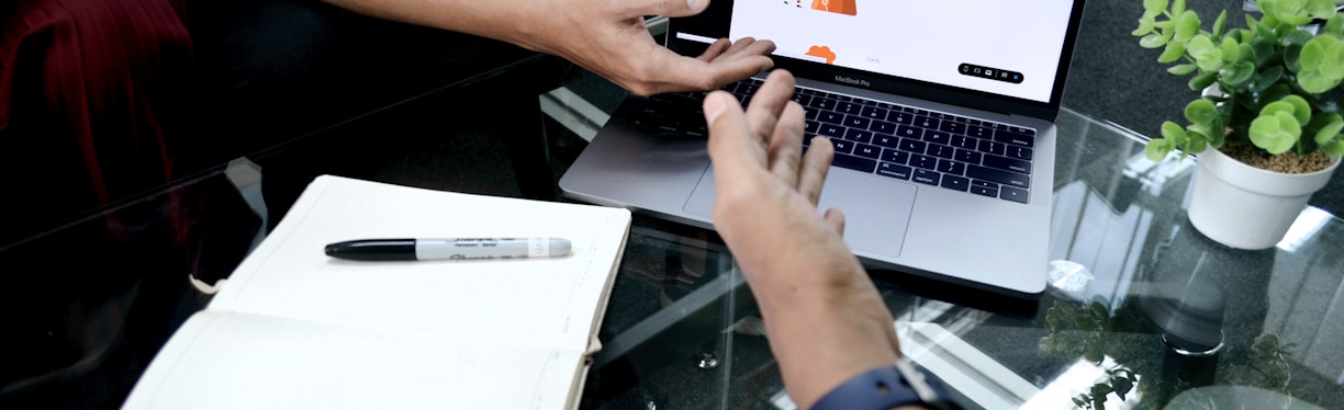 person using macbook pro on white table