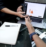 person using macbook pro on white table