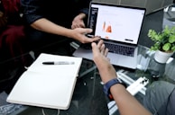 person using macbook pro on white table