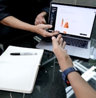 person using macbook pro on white table