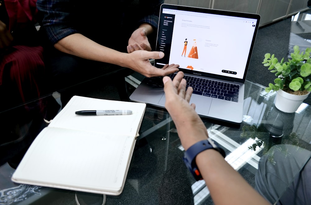 person using macbook pro on white table