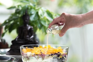 person pouring yellow liquid on clear drinking glass