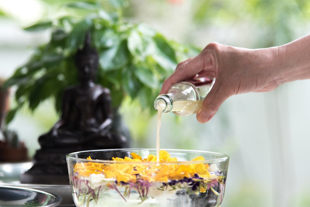 person pouring yellow liquid on clear drinking glass