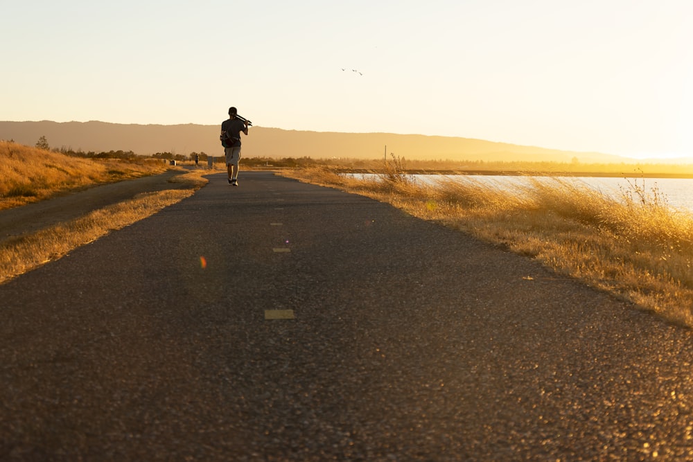 man in black jacket walking on gray asphalt road during daytime