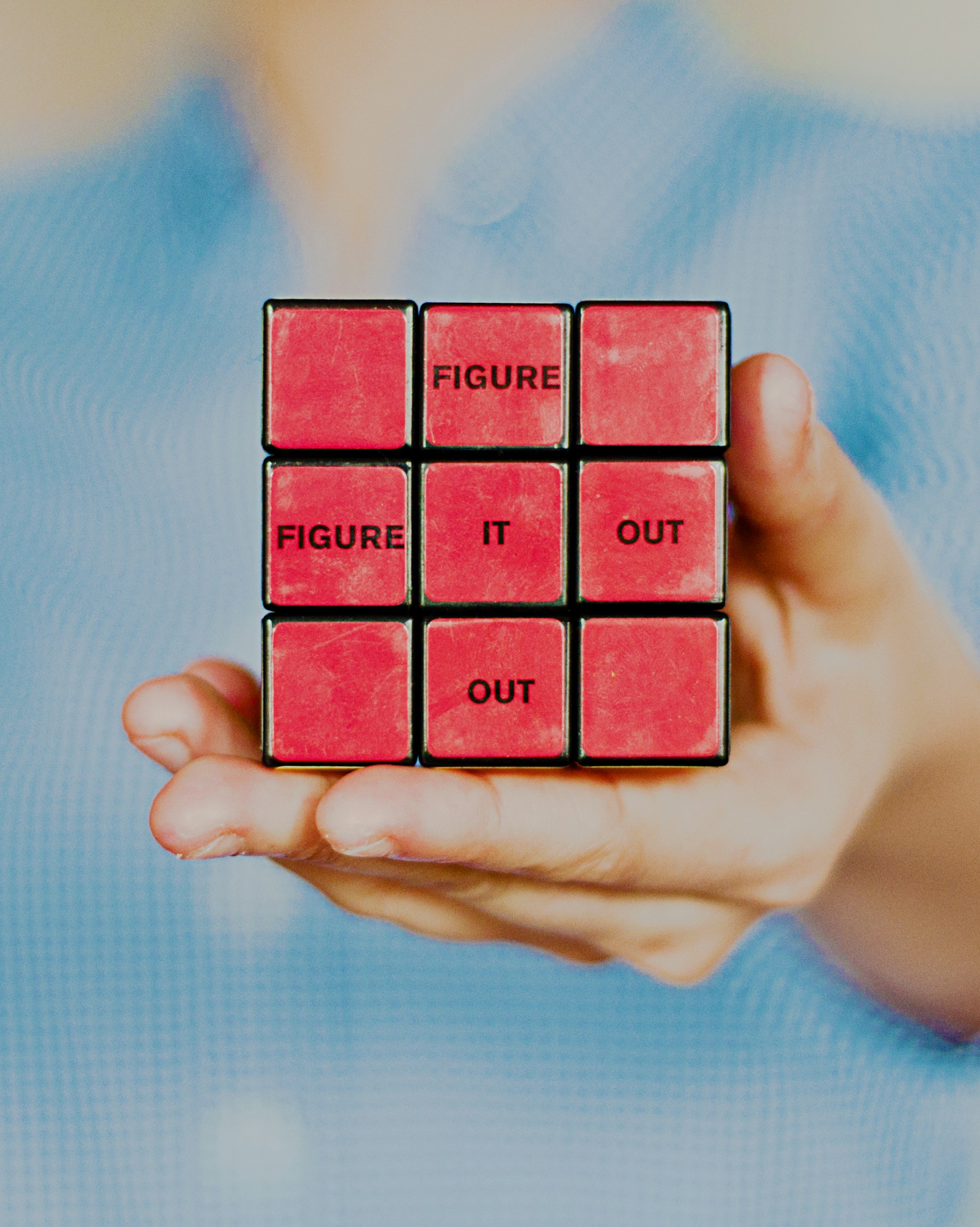 Person holding a solved rubik's cube with the words "figure it out".