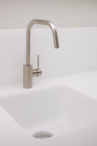 Sleek kitchen faucet with brushed metal finish installed over a white sink.