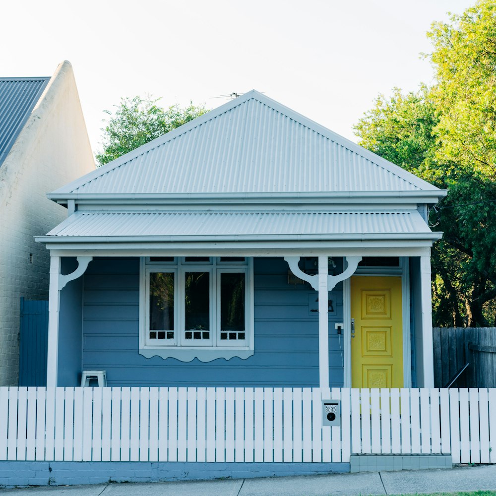 Maison en bois blanc et gris près des arbres verts pendant la journée