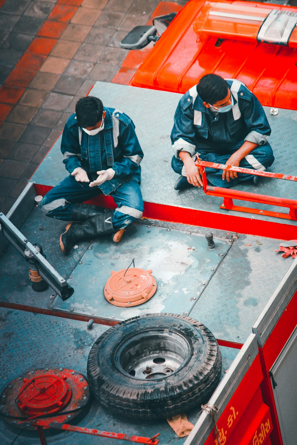 man in blue jacket and blue denim jeans sitting on red metal bar