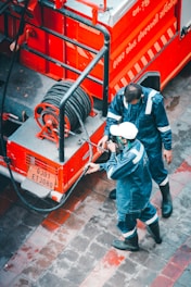 Firefighters connecting hoses to a red fire engine during an emergency.