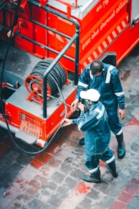 Firefighters connecting hoses to a red fire engine during an emergency.