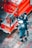 Two people dressed in blue protective gear are handling a hose connected to a red vehicle, possibly a fire truck. The ground is paved with gray and red tiles, and the vehicle has writing in a language other than English, possibly indicating it's for emergency services.