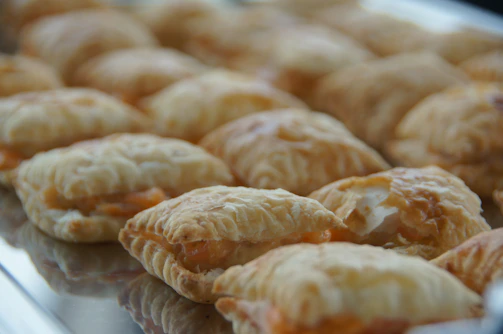 A close-up of golden, flaky Vietnamese pastries arranged on a rustic wooden tray.