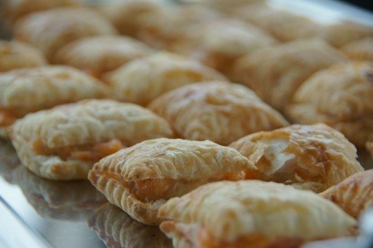 A tray filled with several golden-brown, flaky pastries placed in rows. The pastries have a slightly puffed appearance with a visible layered texture.