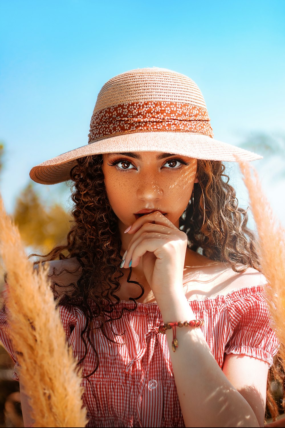 Femme en chemise rouge et blanche portant un chapeau marron