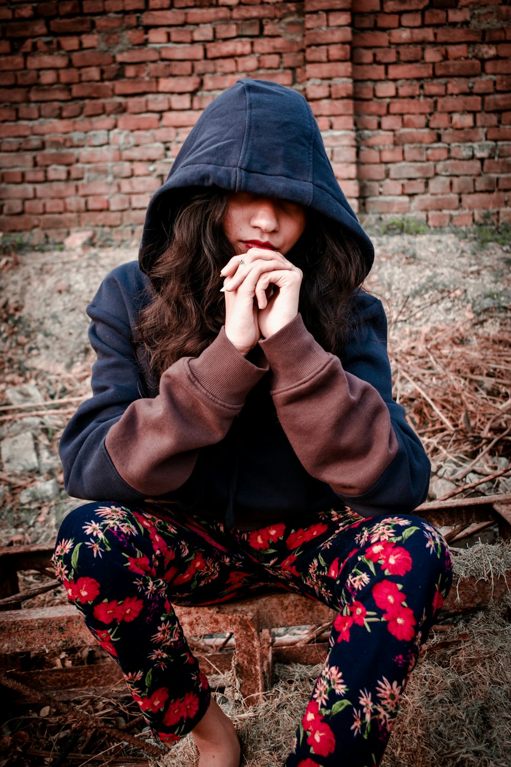 woman in gray hoodie covering her face with her hand