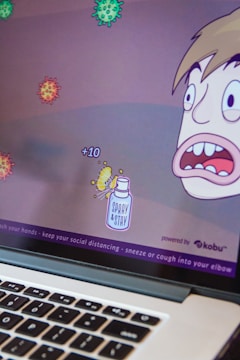 A cartoon-style computer game screen depicts a character with a surprised expression facing several floating virus illustrations. Points are indicated with '+10' near a spray bottle labeled 'Spray & Stay'. The bottom of the screen displays health advice like washing hands and maintaining social distance.