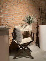 Rustic tan dress draped over a vintage wooden chair beside soft clay pottery.