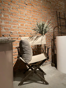 A folded throw with clay-like texture draped over a simple wooden chair in a calm, airy room.