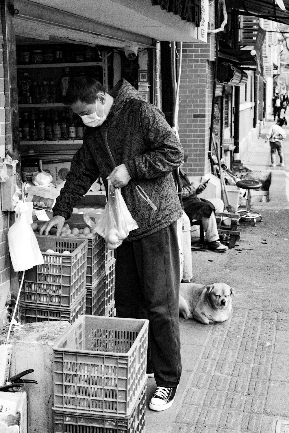 man in black jacket holding a basket with a dog in grayscale photography