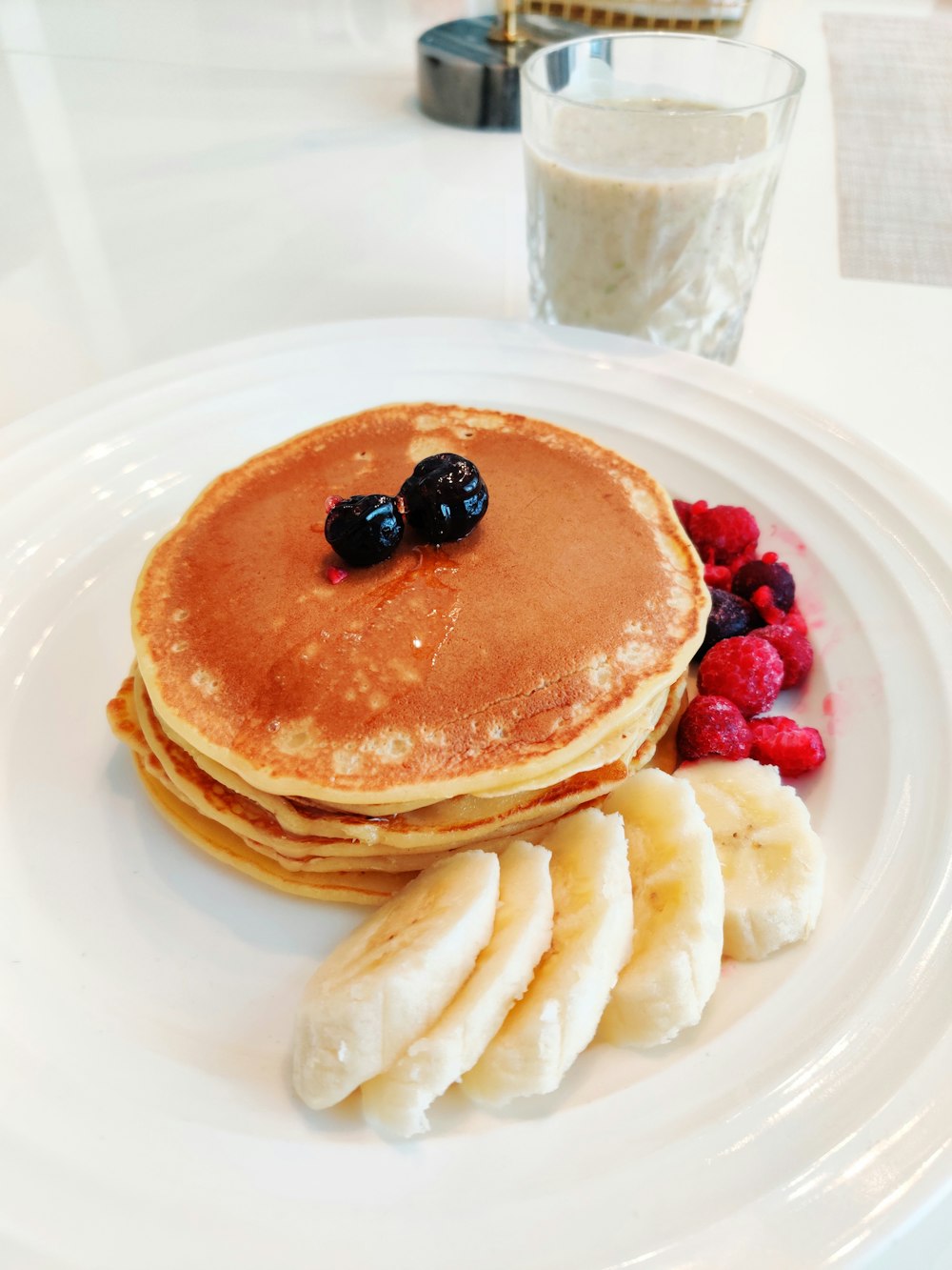 Pfannkuchen mit Beeren auf weißem Keramikteller