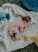 baby in pink onesie lying on white bed