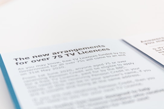 A document page with blue and white background text detailing new arrangements for TV licenses for individuals over 75. The text mentions the end of free TV licenses funded by the government and provides information regarding eligibility and application.