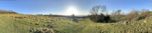 A panoramic view of a spacious, green plot of land under a clear blue sky