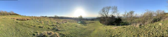 A panoramic view of a spacious, green plot of land under a clear blue sky