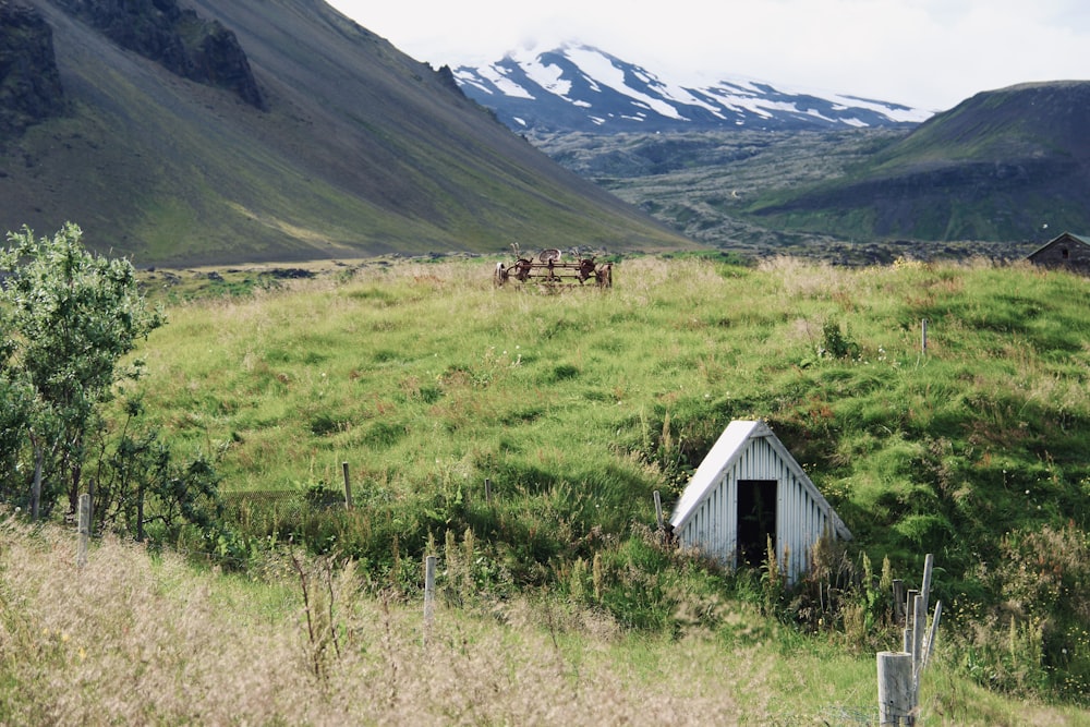 white wooden house on green grass field near mountain during daytime