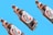 Three glass bottles of Tuborg beer, featuring a white and red label, are angled diagonally against a bright blue background. The bottles are arranged in a pattern, showcasing their design clearly.