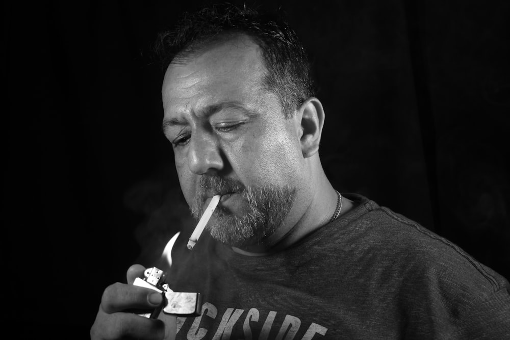 man smoking cigarette in grayscale photography