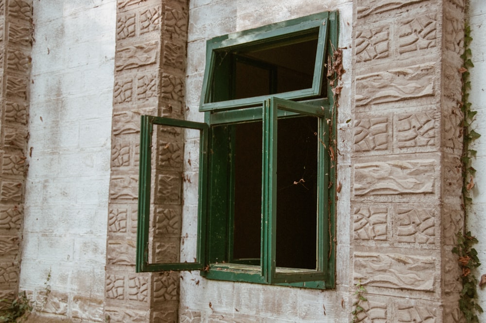 green wooden window frame on brown brick wall