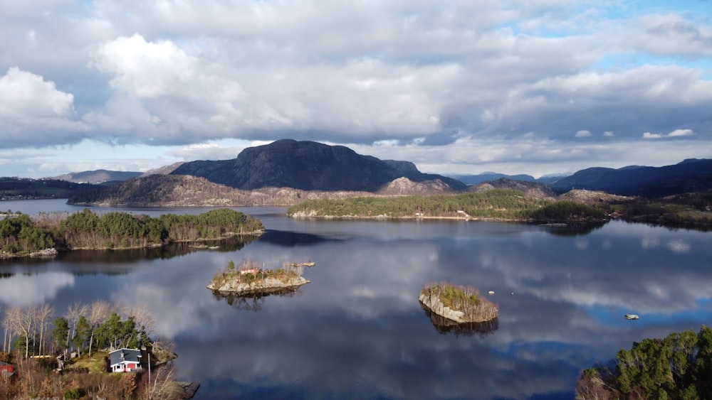 green trees on island surrounded by water under white clouds during daytime