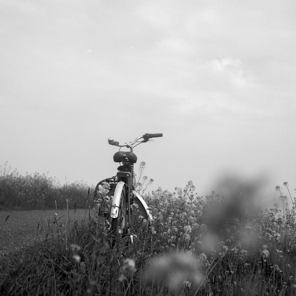 grayscale photo of man riding bicycle on grass field