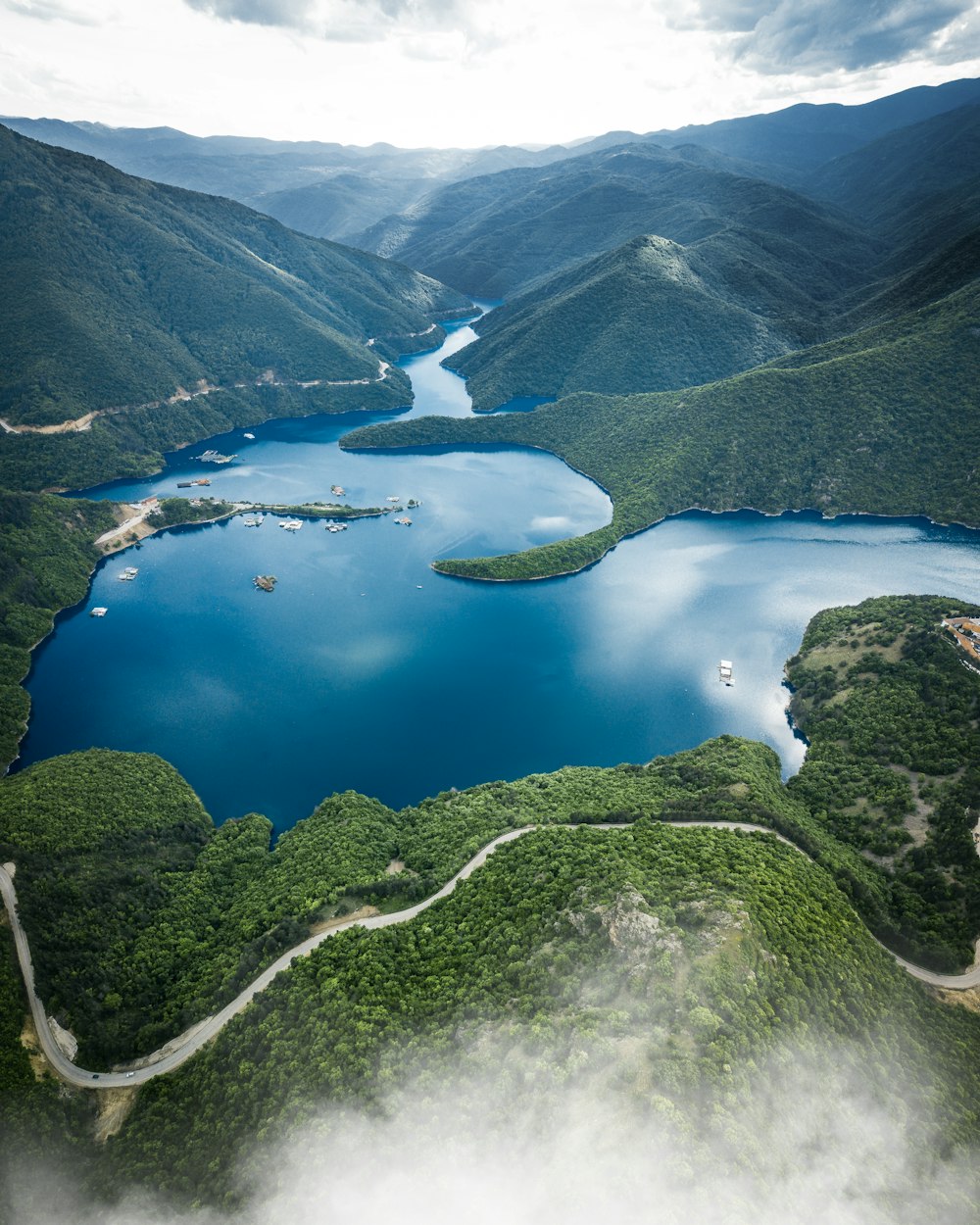 green and white mountain beside lake during daytime